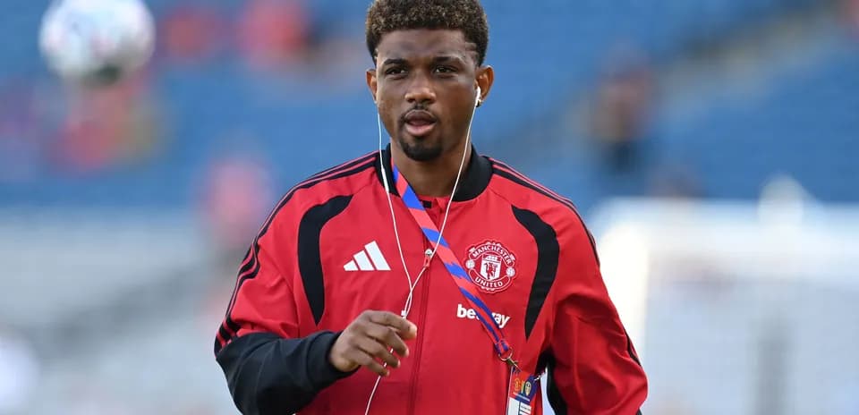 Player in Manchester United kit walking with headphones