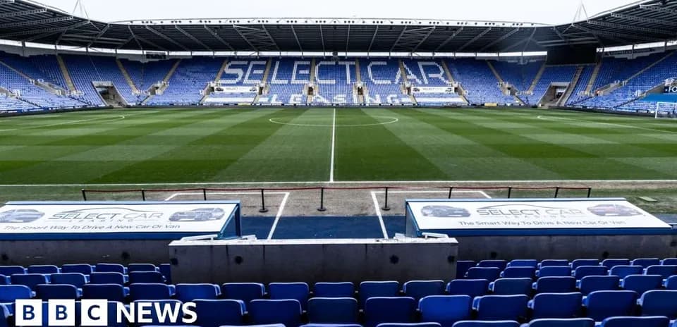 Empty football stadium with blue seats and pitch