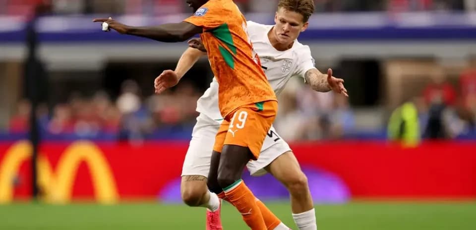 Player in orange jersey dribbling past opponent in white