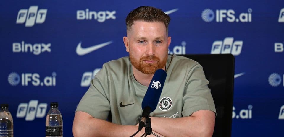 Man speaking at press conference with Chelsea branding