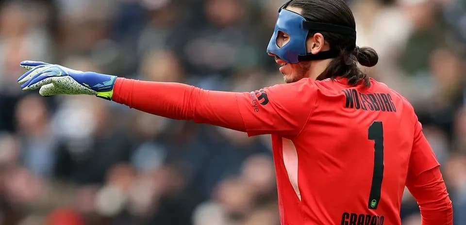 Goalkeeper in red jersey signaling during match