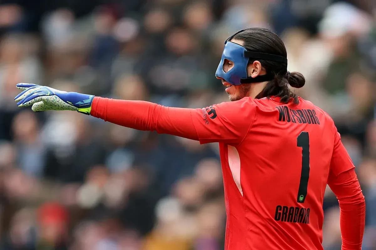 Goalkeeper in red jersey signaling during match