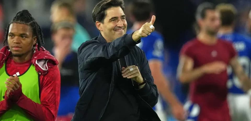 Coach giving thumbs up with players in background