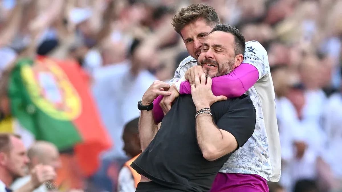 Two coaches celebrating with a hug on the field