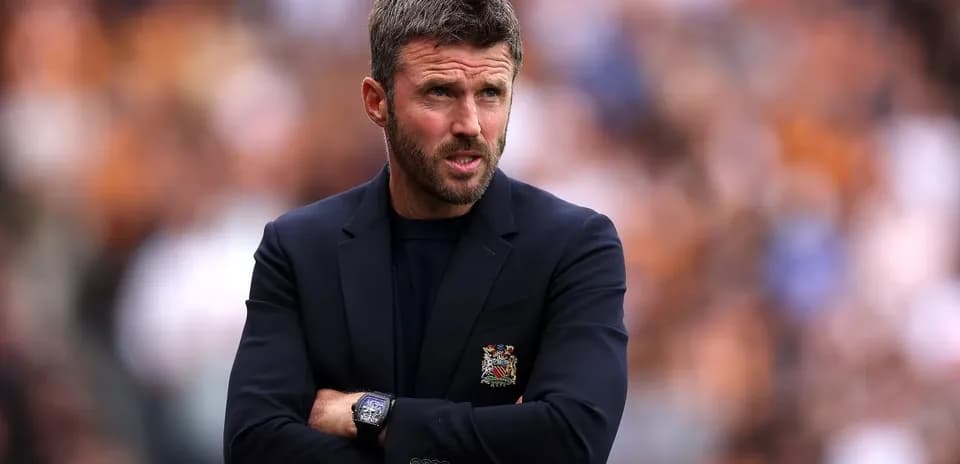 Coach observing match with arms crossed on sidelines