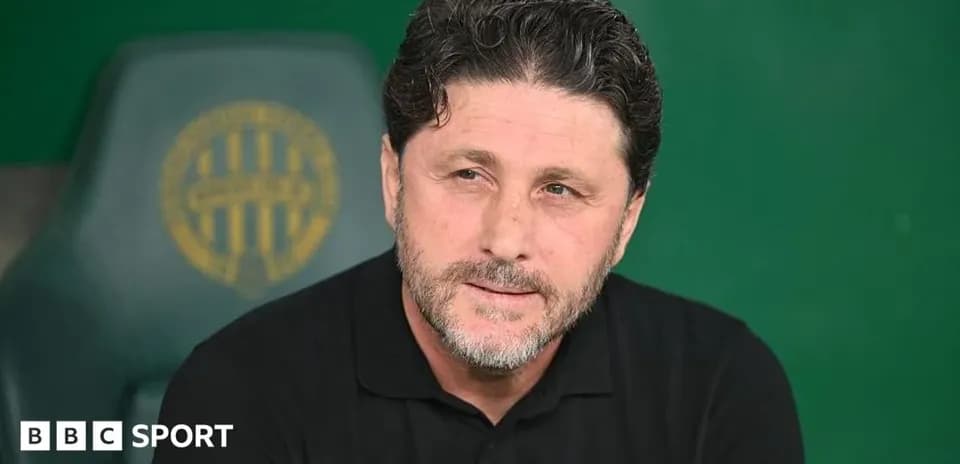 Coach seated on bench during match preparations