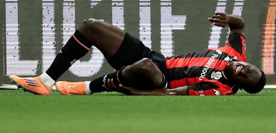 Player lying on ground holding leg in pain