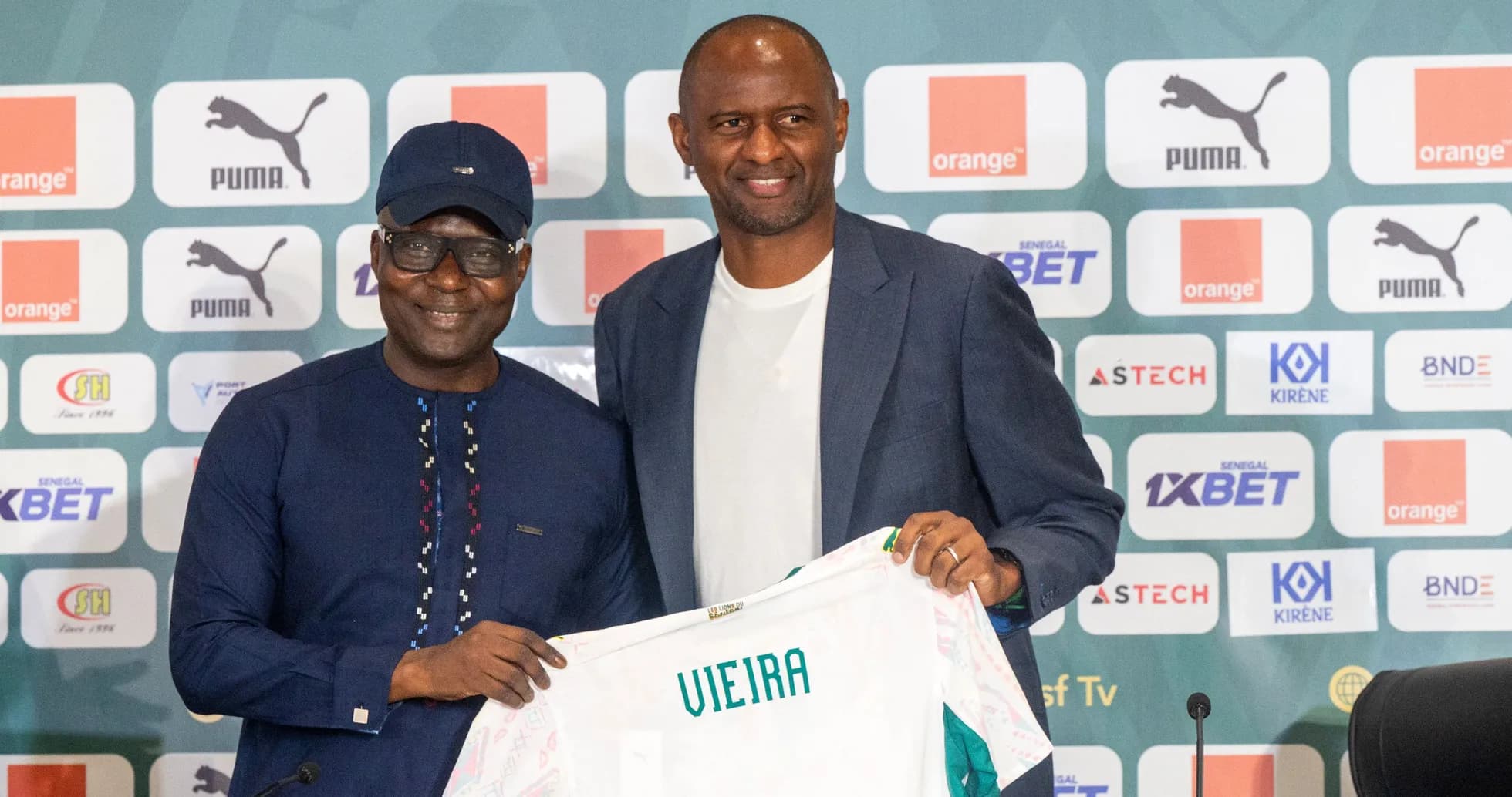 Two men holding a football shirt at a press event