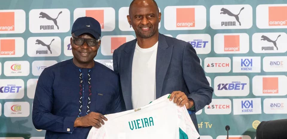 Two men holding a football shirt at a press event