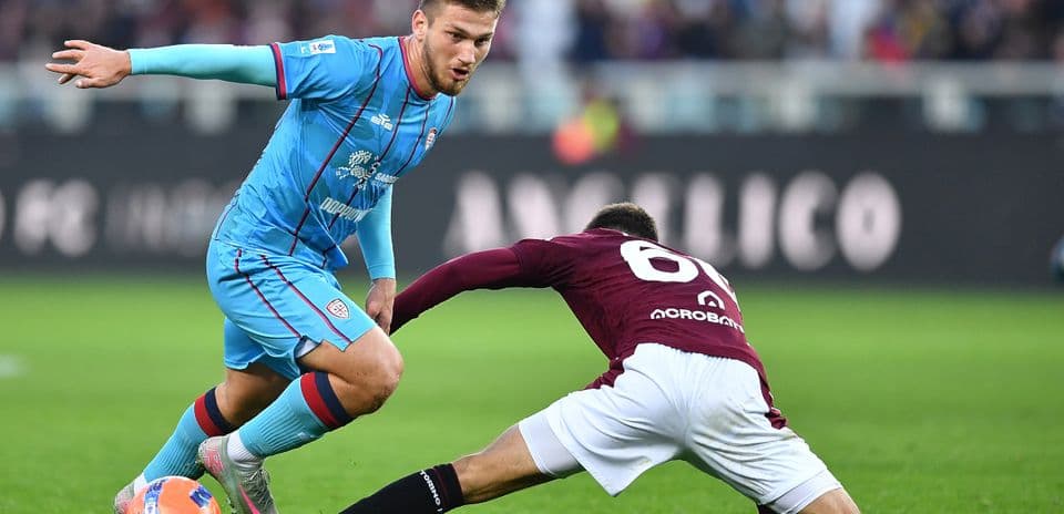 Cagliari player evading Torino tackle during match