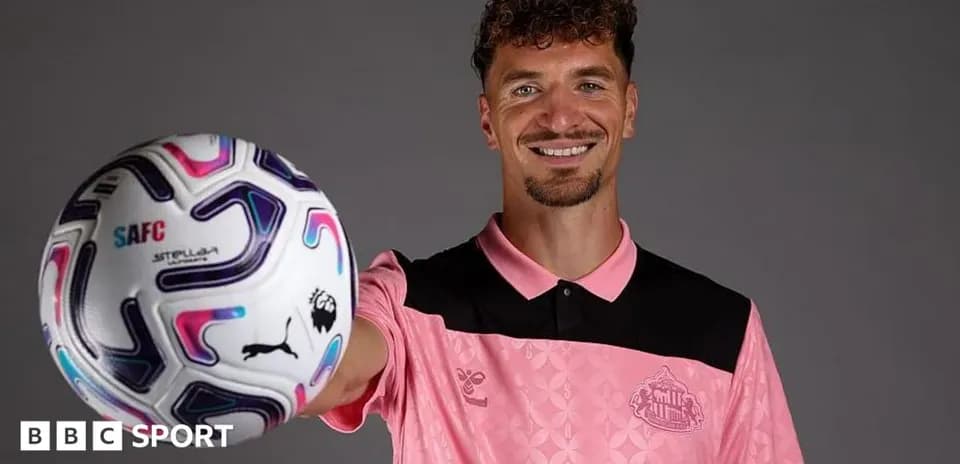 Player holding a soccer ball and smiling