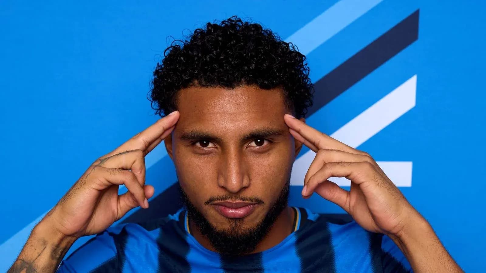 Player posing with hands on head against blue background