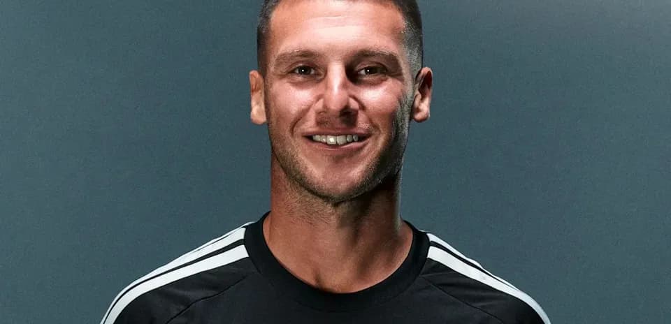 Player posing in black training kit with logo
