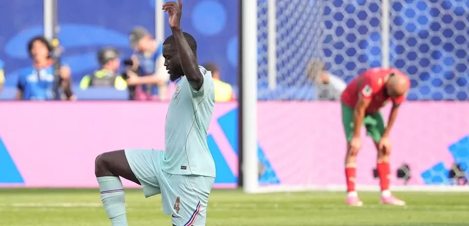 Player kneeling on field during match with opponent nearby