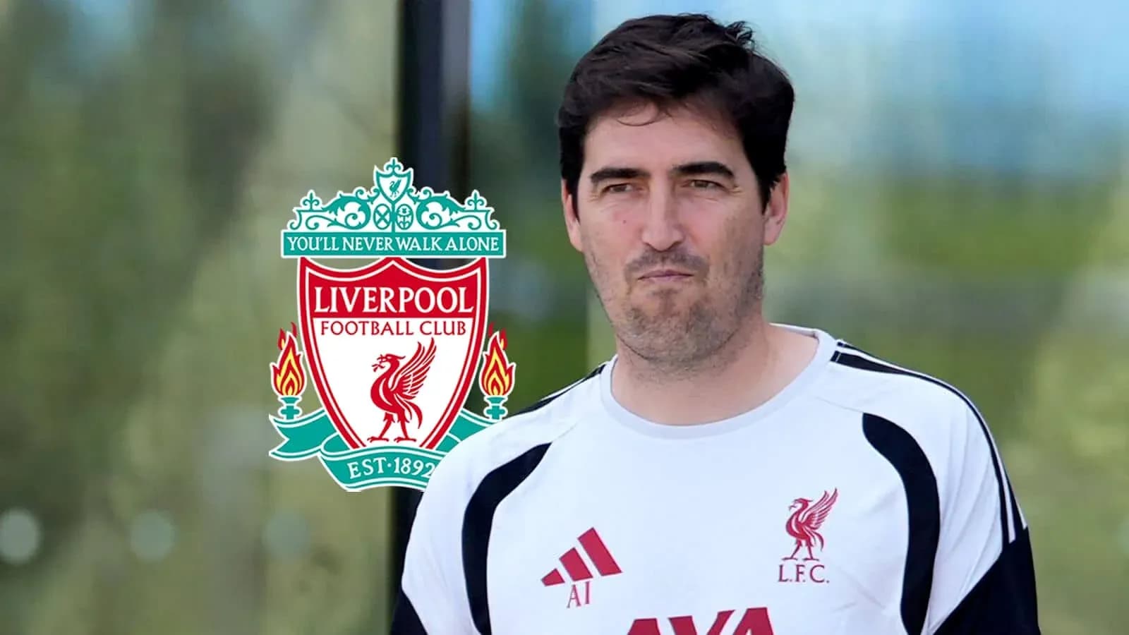 Man in Liverpool FC training gear near club logo