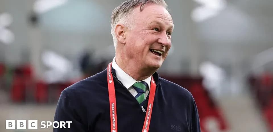Man smiling with lanyard in stadium setting