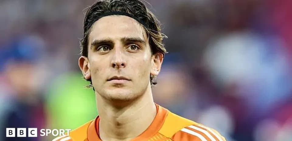 Goalkeeper in orange kit looking at the camera
