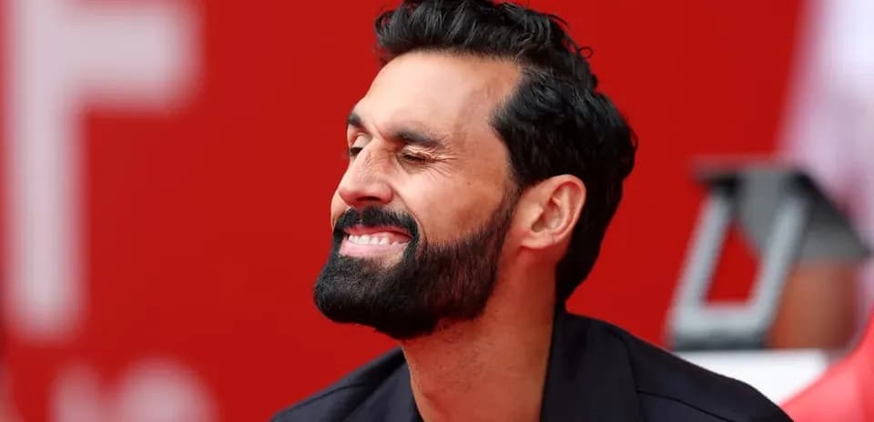 Man smiling and winking in front of red background