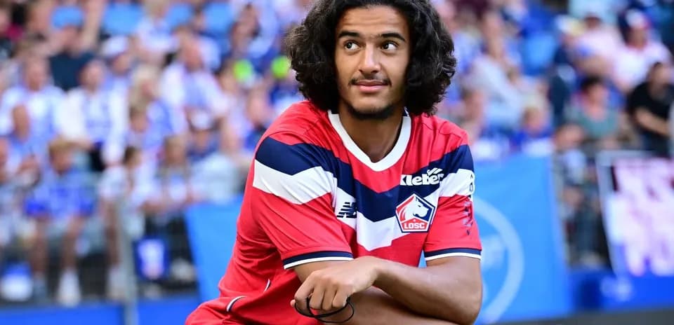 Player in Lille OSC jersey sitting on the pitch