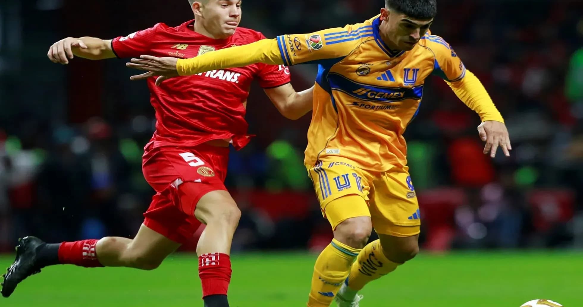 Toluca player challenges Tigres UANL player for the ball
