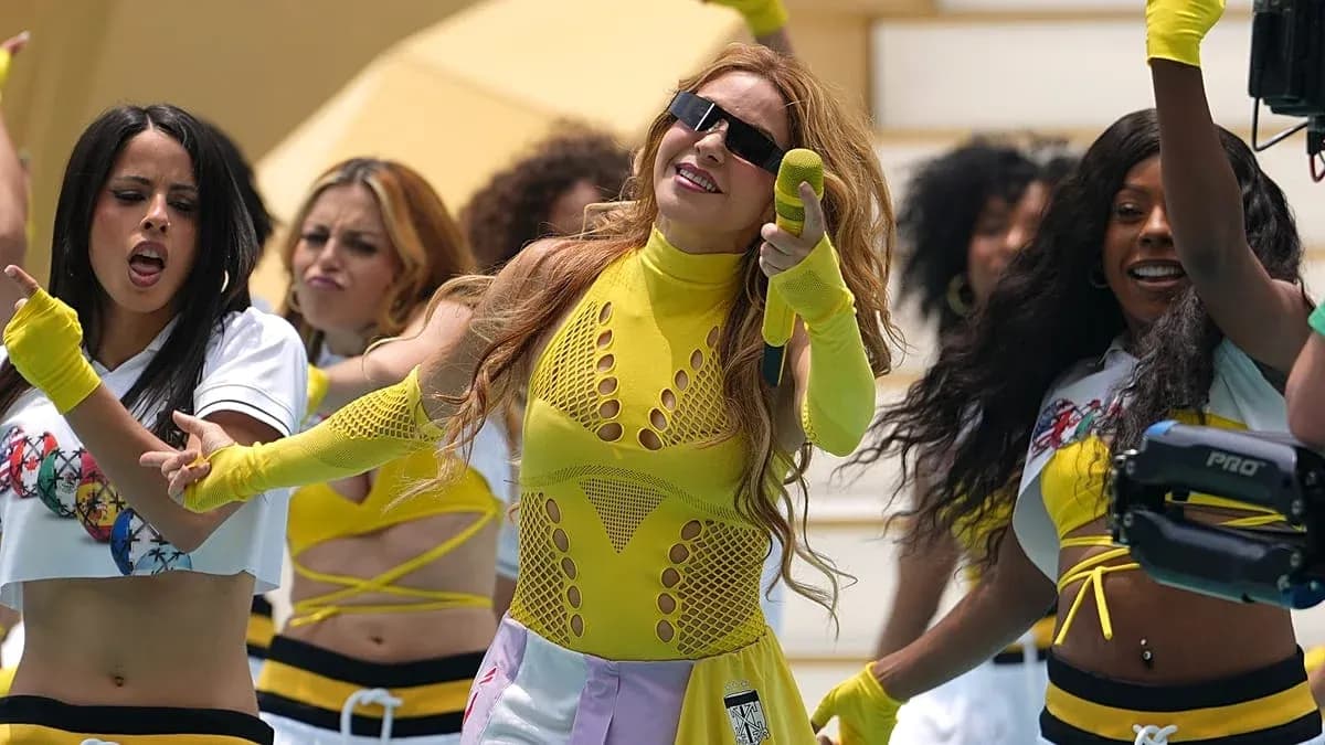 Performer singing with dancers in bright outfits