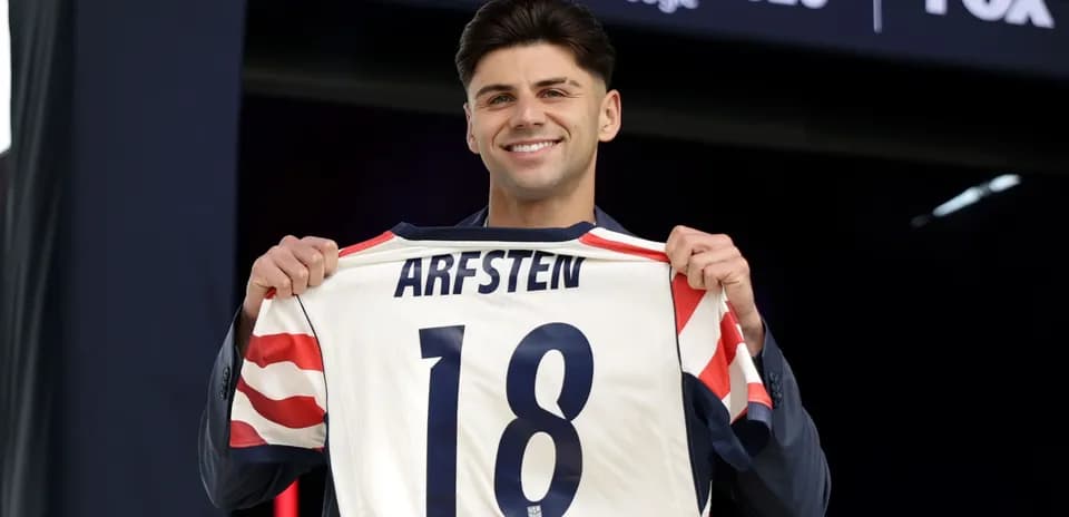 Player holding jersey with 'ARFSTEN 18' at event