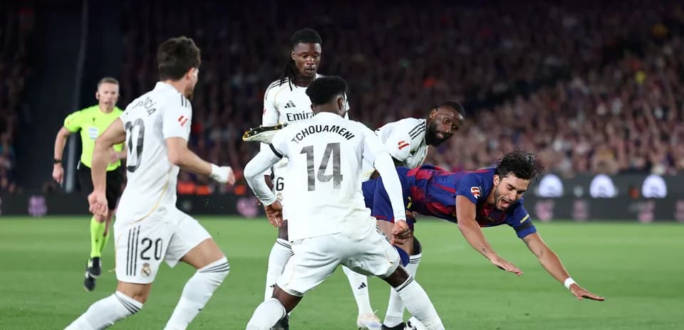 Barcelona player falling while tackled by Real Madrid defenders