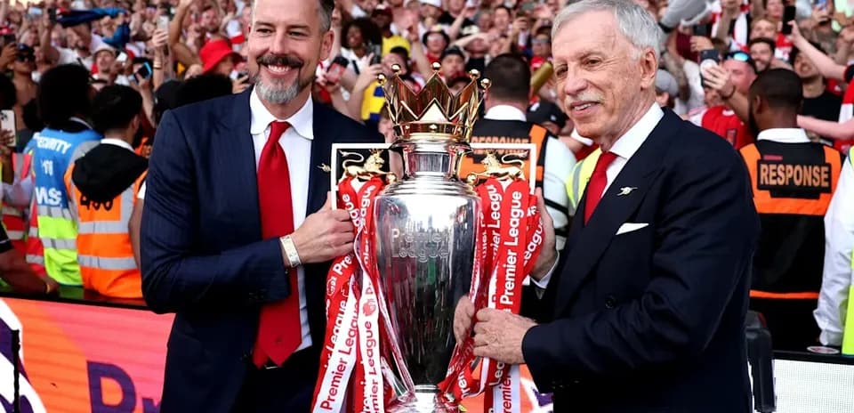 Two men holding the Premier League trophy with fans