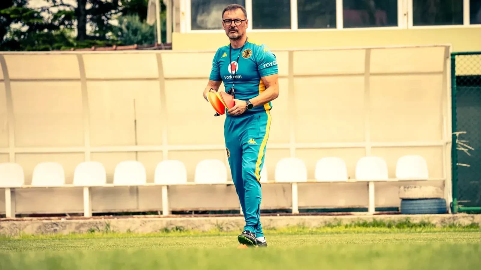 Coach walking on field holding training cones