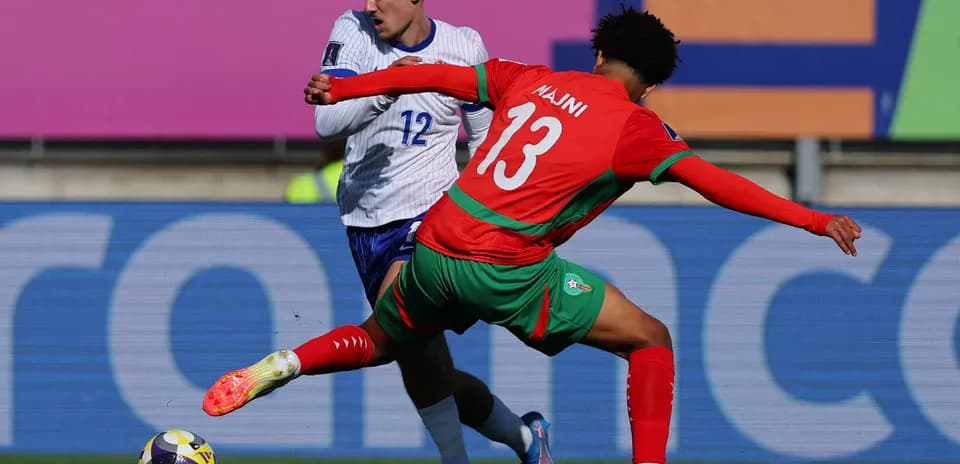 Player in red tackling opponent in white during match