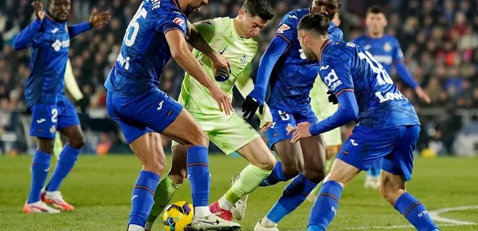 Getafe players challenging Mallorca player for the ball