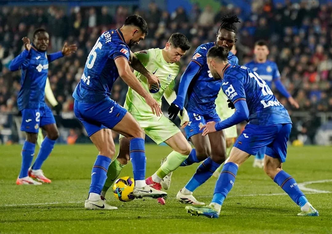 Getafe players challenging Mallorca player for the ball