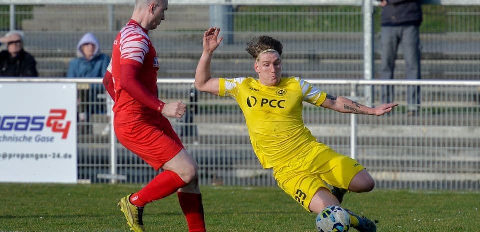 Player sliding tackle during Büderich vs SF Baumberg match