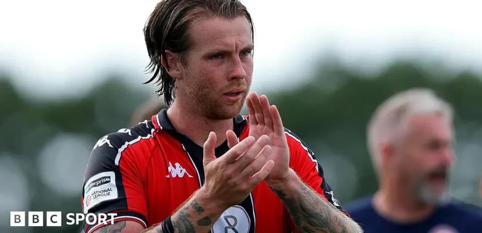 Player applauding fans after match wearing red jersey