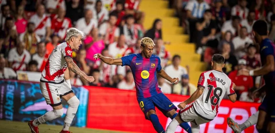 Barcelona player dribbling against Rayo Vallecano defenders