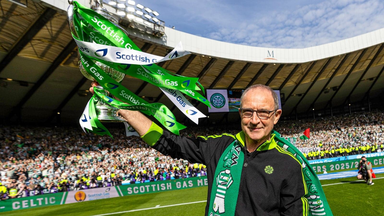 Man celebrating with trophy and Celtic scarf