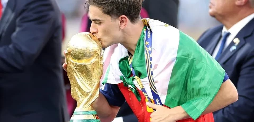 Player kissing the World Cup trophy wearing flag