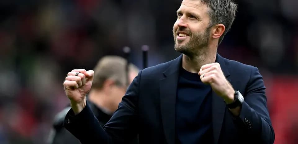 Coach celebrating with clenched fist on pitch
