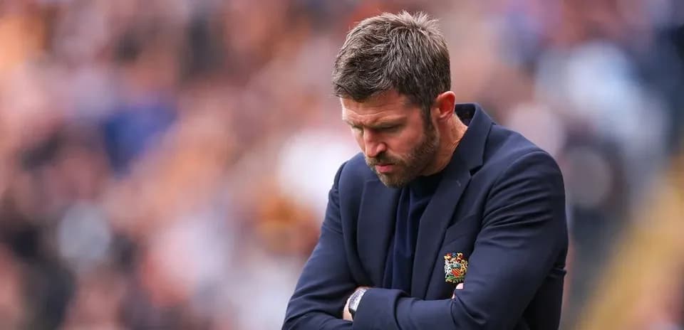 Coach with arms crossed looking down during match