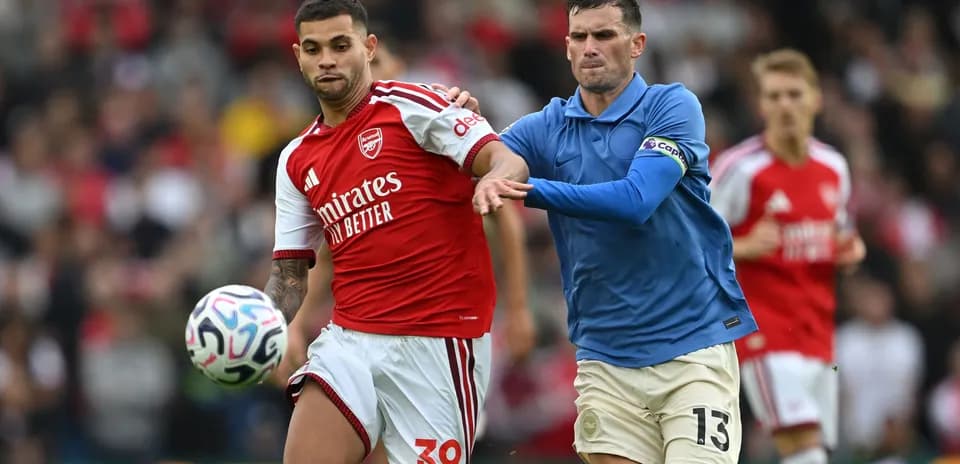 Arsenal player dribbling past opponent during match