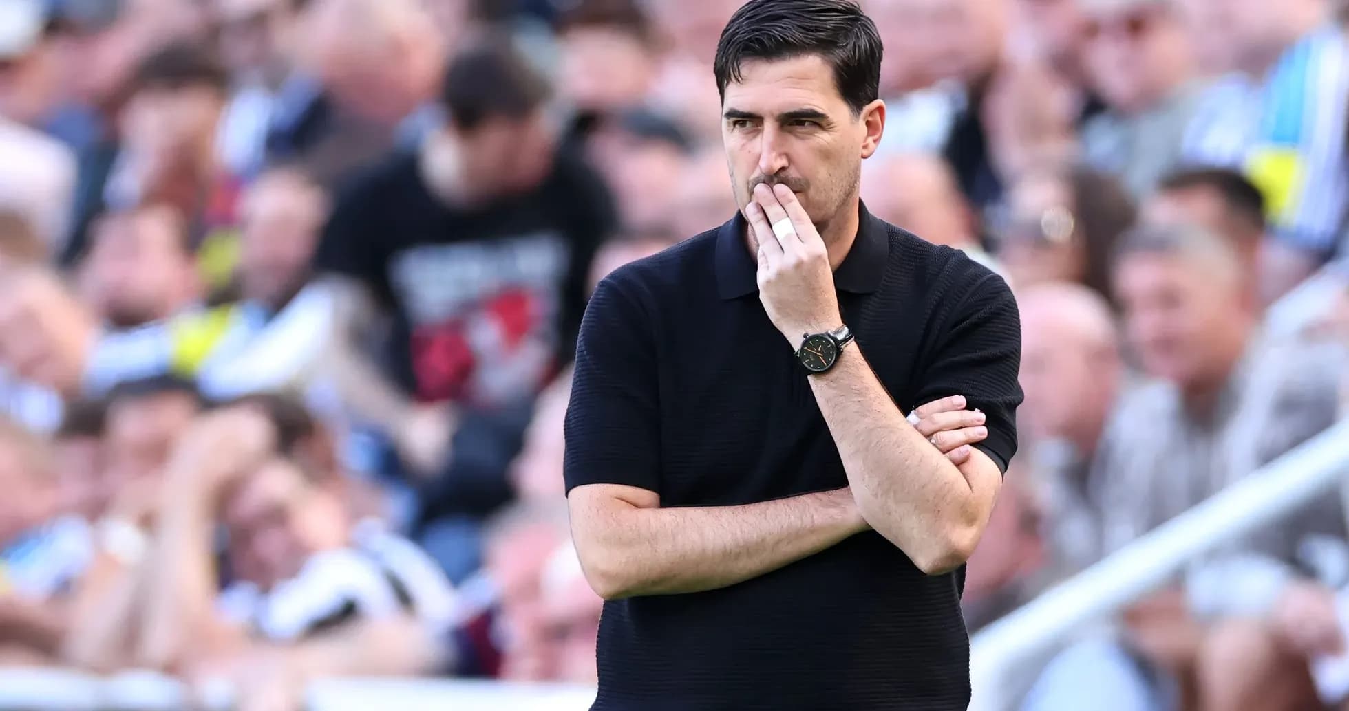 Coach observing match with arms crossed in crowd