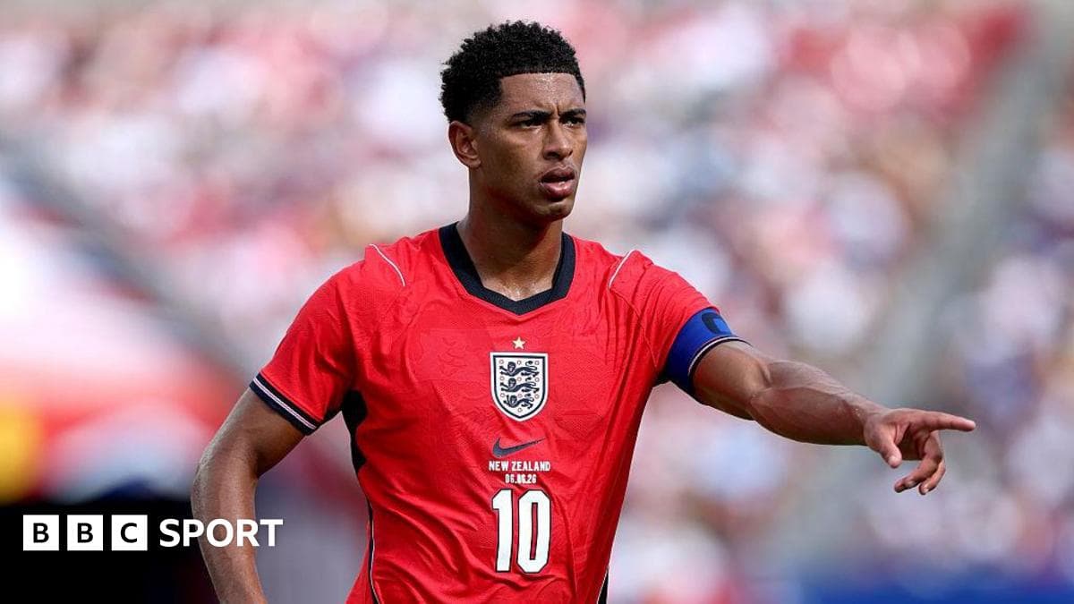 Player in red England kit directing teammates on field