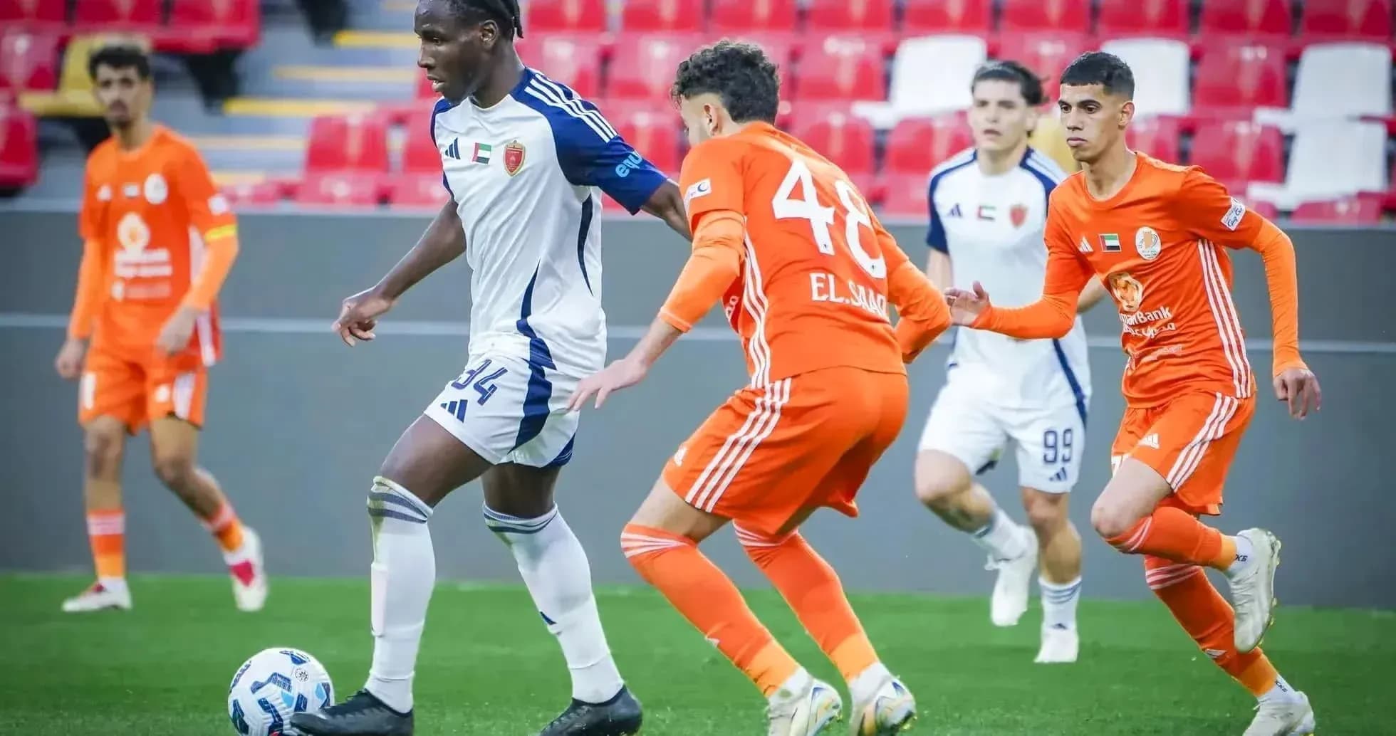Khorfakkan U23 player dribbling past Al Sharjah U23 defenders