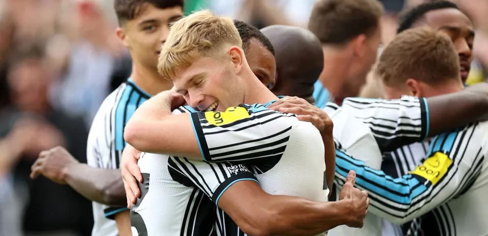 Newcastle players celebrating with hugs after a goal