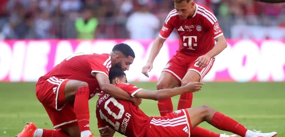 Bayern Munich players assisting teammate on field