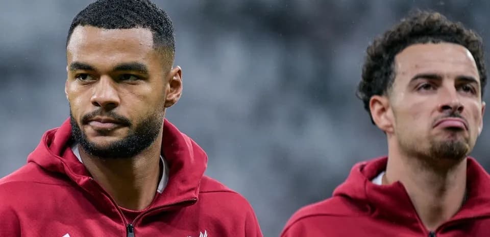 Two Liverpool players in training jackets on field