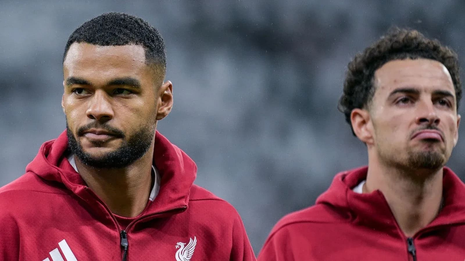 Two Liverpool players in training jackets on field