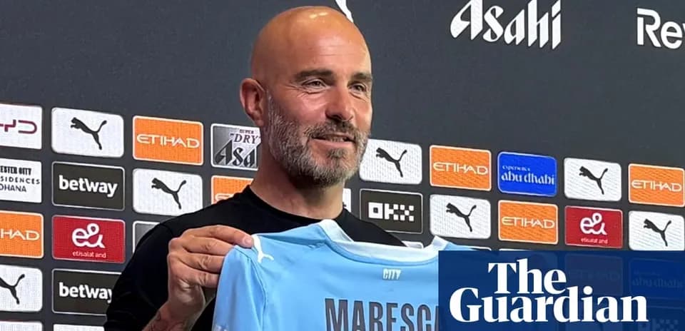 Coach holding Manchester City jersey at press conference