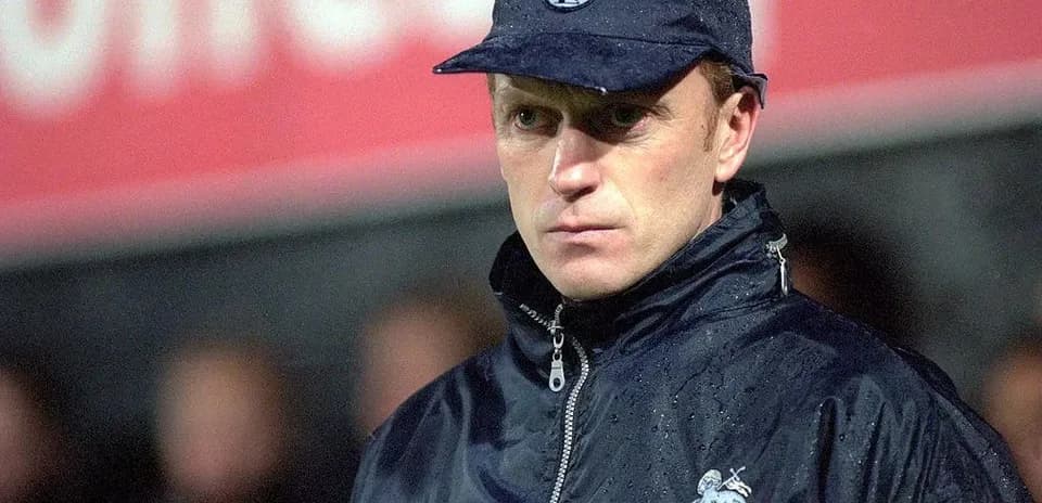 Coach wearing cap during a rainy match