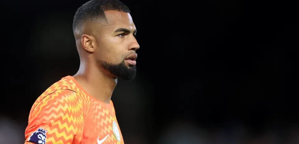 Goalkeeper in orange kit during match warm-up